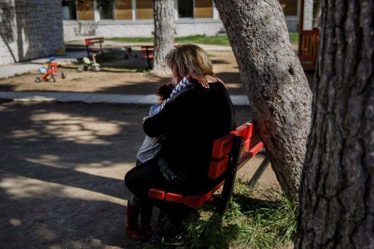 A child hugs a teacher at the yard of the Model National Nursery of Kallithea, in Athens, Greece, March 3, 2017.