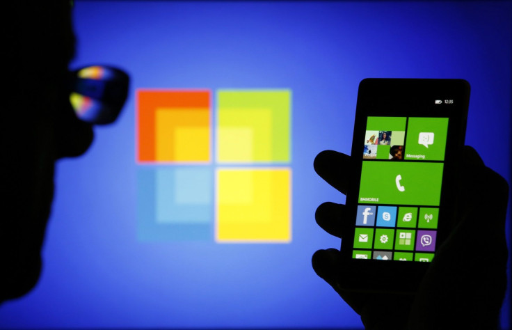 A man is silhouetted against a video screen with as he poses with a Nokia Lumia 820 smartphone in this photo illustration taken in the central Bosnian town of Zenica, September 3, 2013