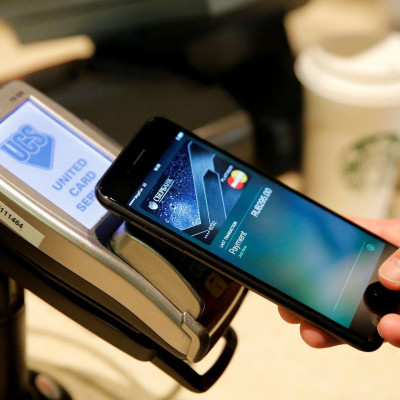 FILE PHOTO: A man uses an iPhone 7 smartphone to demonstrate the mobile payment service Apple Pay at a cafe in Moscow, Russia, October 3, 2016.