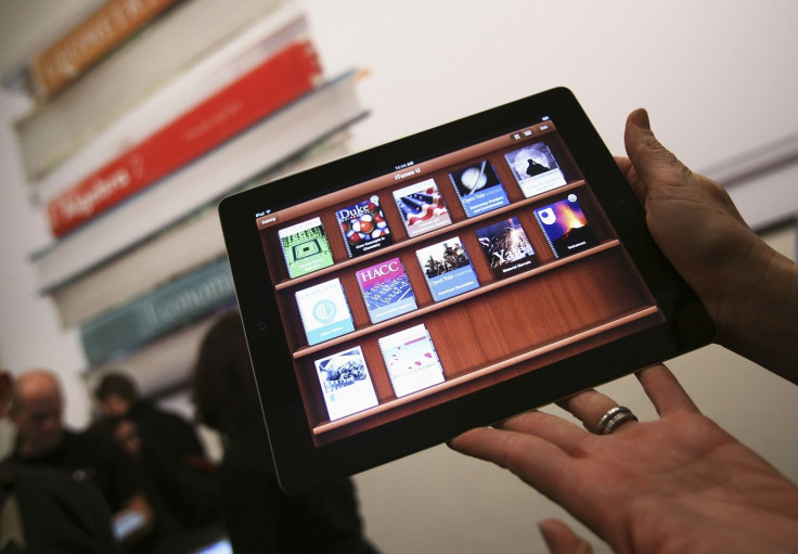 A woman holds up an iPad with the iTunes U app after a news conference introducing a digital textbook service in New York January 19, 2012.