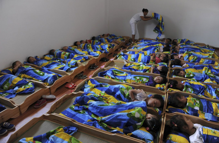 A teacher covers a child with a quilt as children take an afternoon nap at a kindergarden in Jiaxing, Zhejiang province September 14, 2011.