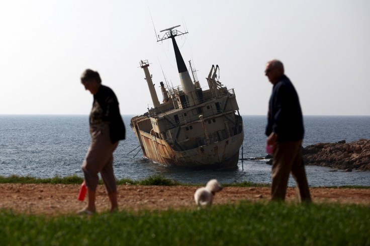 Tourists walk near a shipwreck in the coastal village of Pegeia, Cyprus February 28, 2016.
