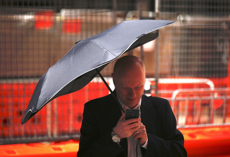 A man uses his phone as he holds an umbrella crossing a street in the central business district (CBD) of Sydney in Australia, February 13, 2018.