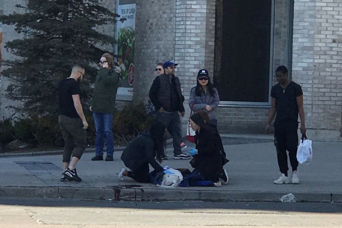 A victim is helped by pedestrians after a van hit multiple people at a major intersection in Toronto, Canada April 23, 2018, in this picture obtained by Reuters