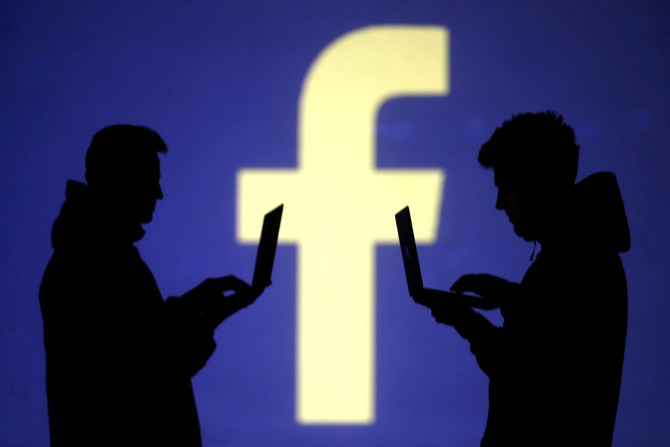 FILE PHOTO: Silhouettes of laptop users are seen next to a screen projection of Facebook logo in this picture illustration taken March 28, 2018.