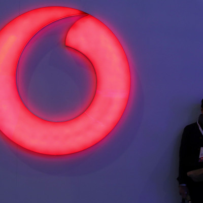 A man checks his mobile phone next to a Vodafone logo at the Mobile World Congress in Barcelona, Spain, February 28, 2018.