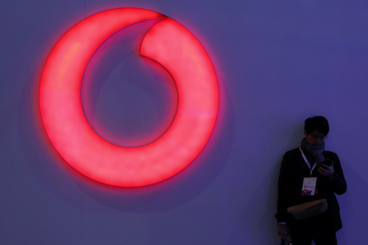 A man checks his mobile phone next to a Vodafone logo at the Mobile World Congress in Barcelona, Spain, February 28, 2018.