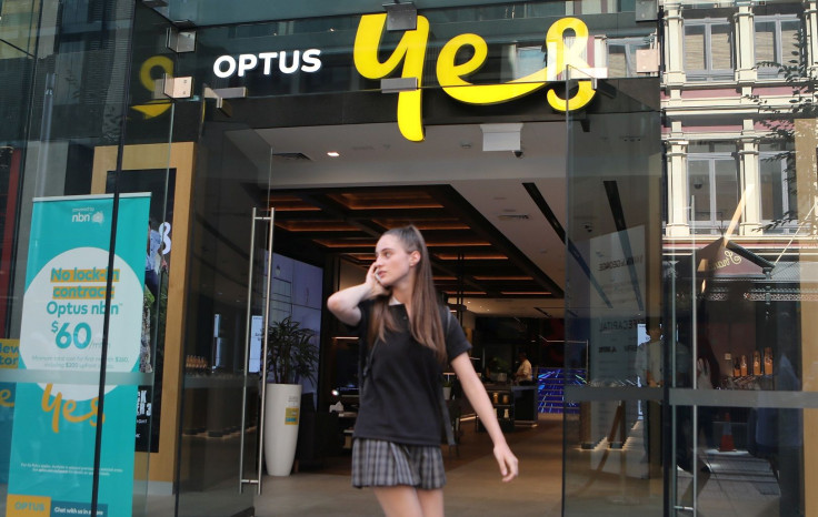 A woman uses her mobile phone as she walks past in front of an Optus shop in Sydney, Australia, February 8, 2018.