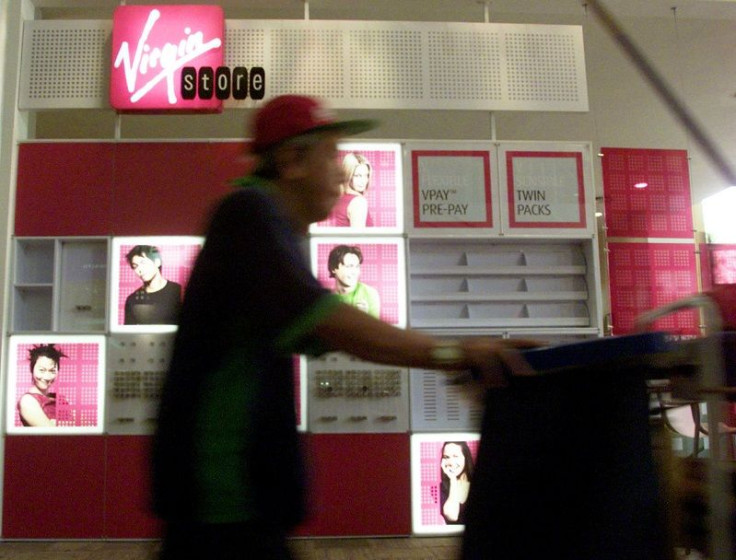 A cleaner walks past a Virgin Mobile stand at a shopping complex in Singapore July 24, 2002.