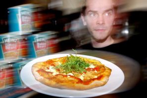 Waiter Will Phillips delivers a baked beans pizza at a new restaurant called "Beans Meanz Heinz" in Melbourne May 26, 2004.
