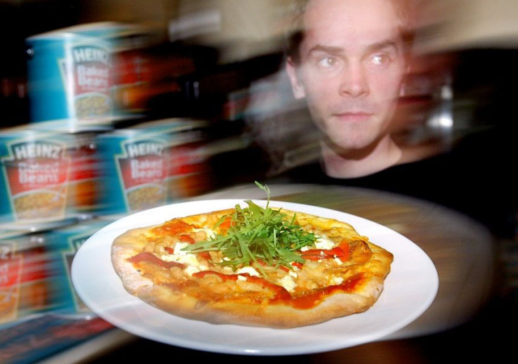 Waiter Will Phillips delivers a baked beans pizza at a new restaurant called "Beans Meanz Heinz" in Melbourne May 26, 2004.