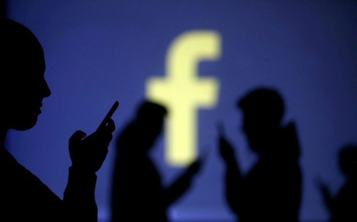 FILE PHOTO: Silhouettes of mobile users are seen next to a screen projection of Facebook logo in this picture illustration taken March 28, 2018.