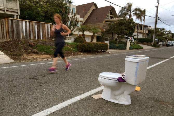 An early morning runner jogs past a toilet placed on the side of the road for free pick-up to any passerby in Leucadia, California, United States May 24, 2016.
