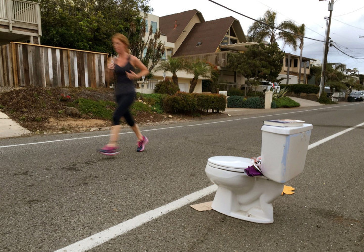 An early morning runner jogs past a toilet placed on the side of the road for free pick-up to any passerby in Leucadia, California, United States May 24, 2016.