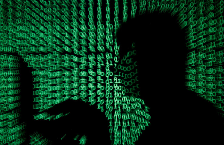 FILE PHOTO: A man holds a laptop computer as cyber code is projected on him in this illustration picture taken on May 13, 2017.