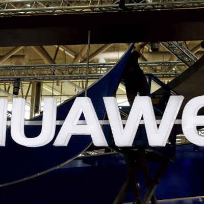 FILE PHOTO: A worker adjusts the logo at the stand of Huawei at the CeBIT trade fair in Hanover, in this file picture taken March 15, 2015.