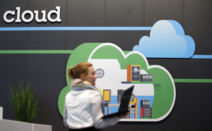 A women holds her laptop as she walks in front of a cloud computing logo at the booth of IBM during preparations for the CeBIT trade fair in Hanover, March 9, 2014.