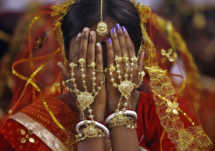 A bride covers her face as she waits to take her wedding vow at a mass marriage ceremony at Bahirkhand village, north of Kolkata February 8, 2015.