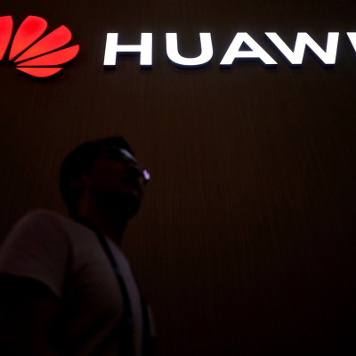 FILE PHOTO: A man walks past a sign board of Huawei at CES (Consumer Electronics Show) Asia 2018 in Shanghai, China June 14, 2018.