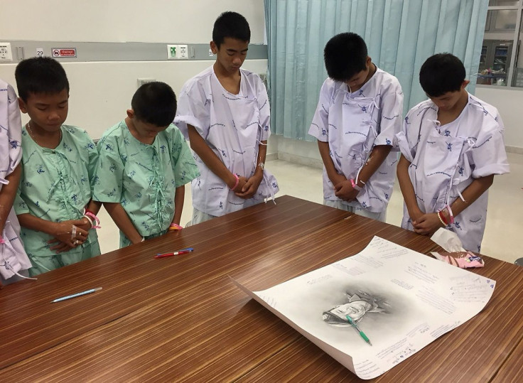 Members of "Wild Boars" soccer team and their coach rescued from a flooded cave bow their heads after writing messages on a drawing picture of Samarn Kunan