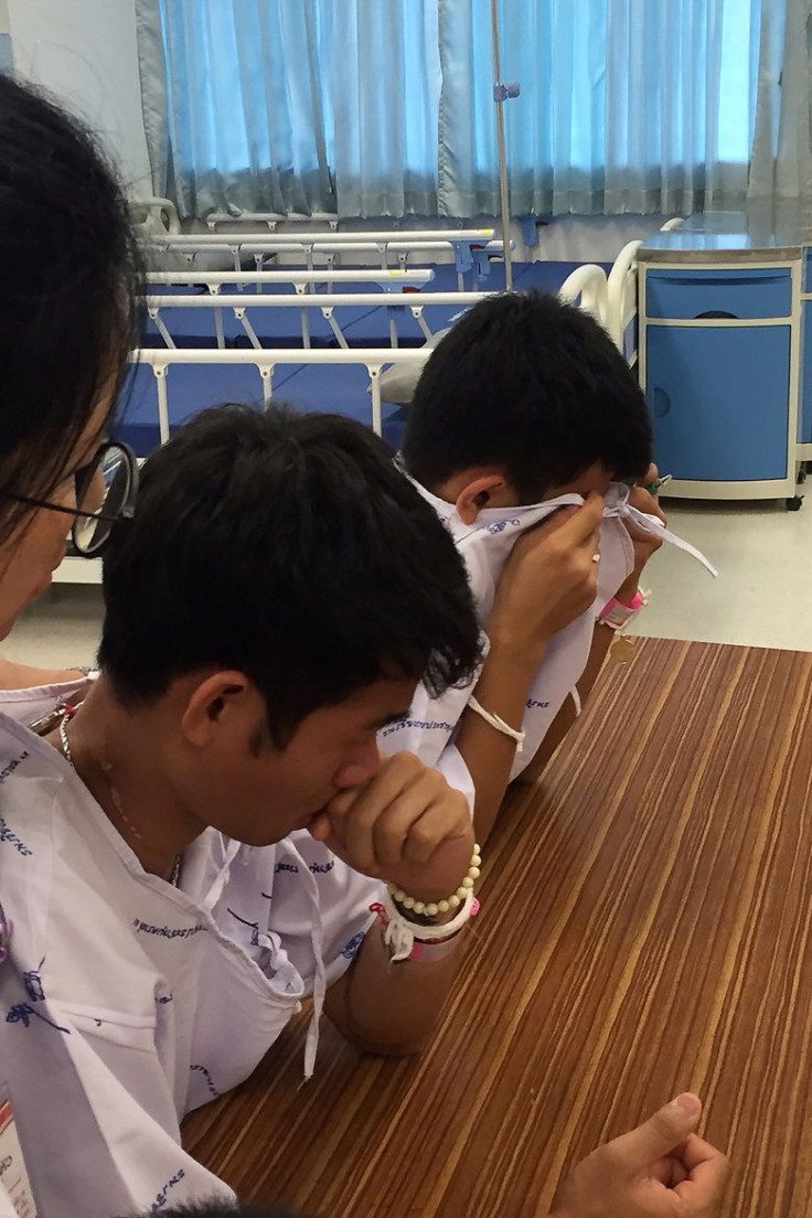 Members of the "Wild Boars" soccer team and their coach, rescued from a flooded cave, cry after writing messages on a drawing of Samarn Kunan