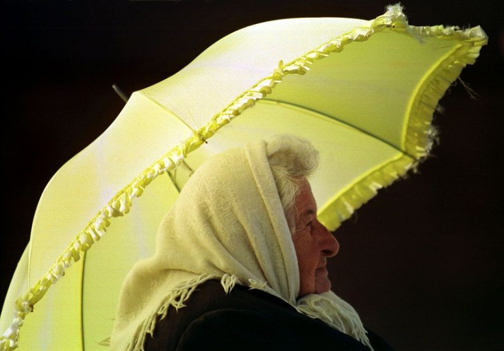 An elderly lady shields herself from the sun with an umbrella while waiting for a bus in Sydney October 14.