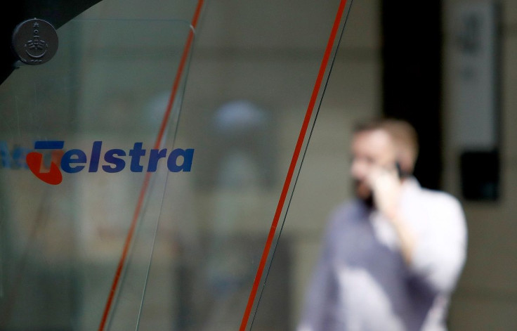 A man uses his mobile phone behind a Telstra logo in central Sydney, Australia, February 8, 2018.