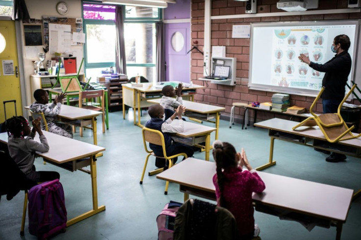 A teacher shows pupils how to clean their hands in a classroom at Saint-Exupery school in the Paris' suburb of La Courneuve