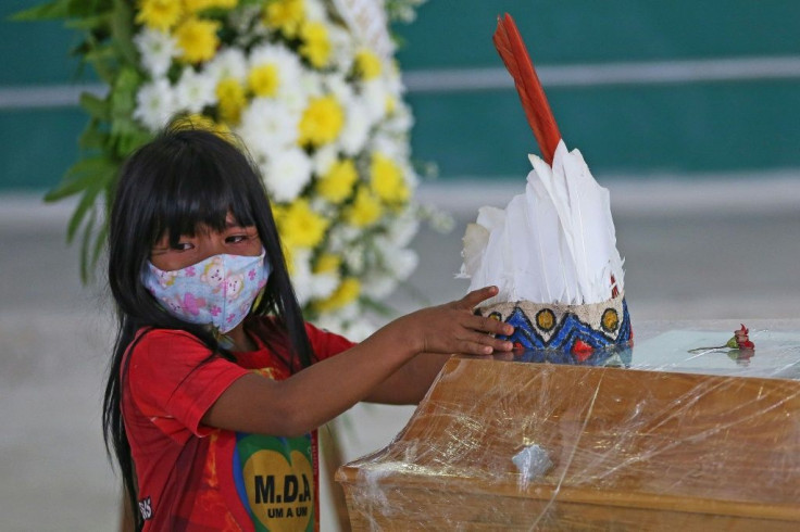 An indigenous girl from Parque das Tribos community leaves a headdress on the coffin of Chief Messias, 53, of the Kokama tribe who died of COVID-19, in Manaus, Brazil