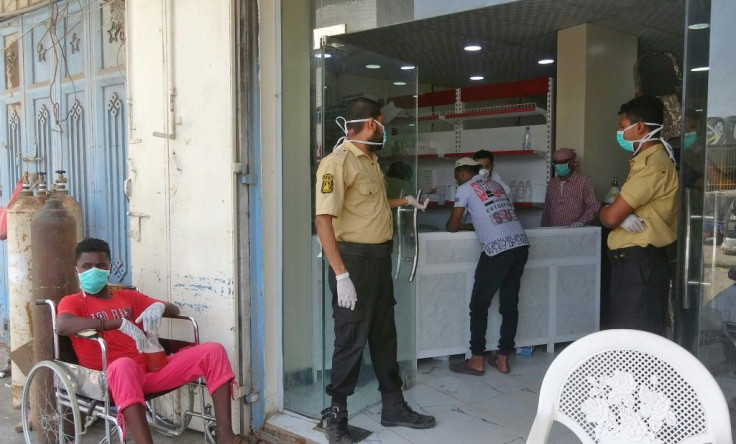 Mask-clad security guards and a patient at the entrance to al-Kubi hospital in Yemen's southern coastal city of Aden