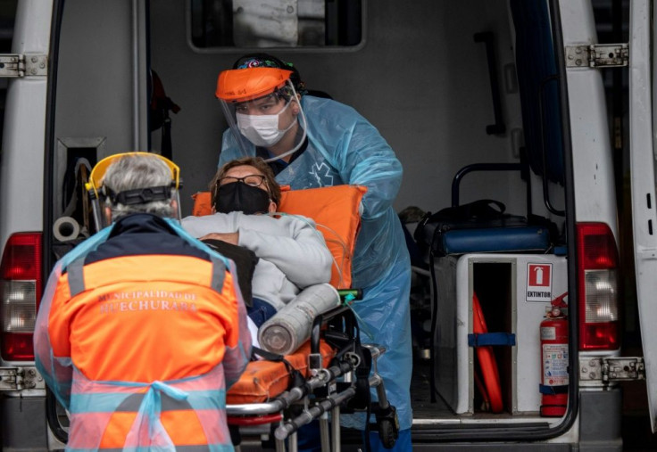 Health workers carry a patient with symptoms of the new COVID-19 coronavirus from an ambulance into a hospital in Santiago