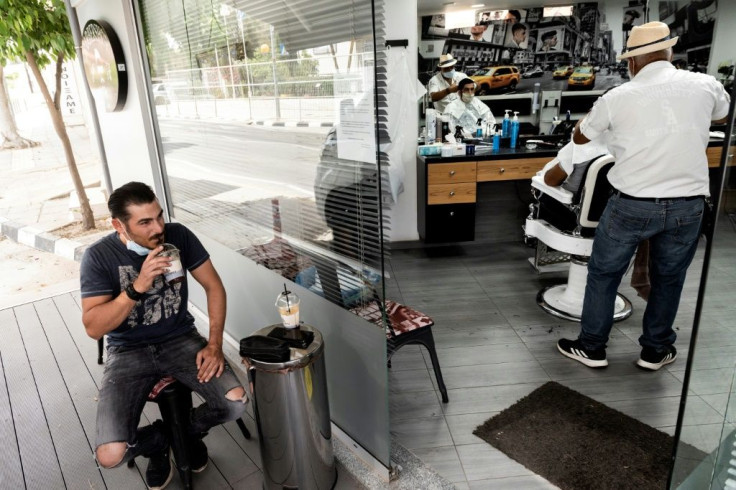Cyprus has moved into a new phase of opening up -- here, a man drinks a chilled coffee drink outside a hairdresser's salon in the capital Nicosia