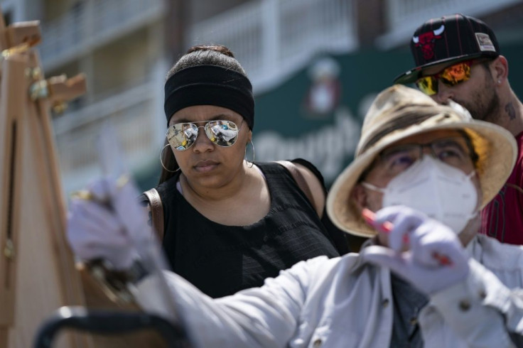 A local artist and onlookers wear masks on the boardwalk during the Memorial Day holiday weekend on May 23, 2020 in Ocean City, Maryland