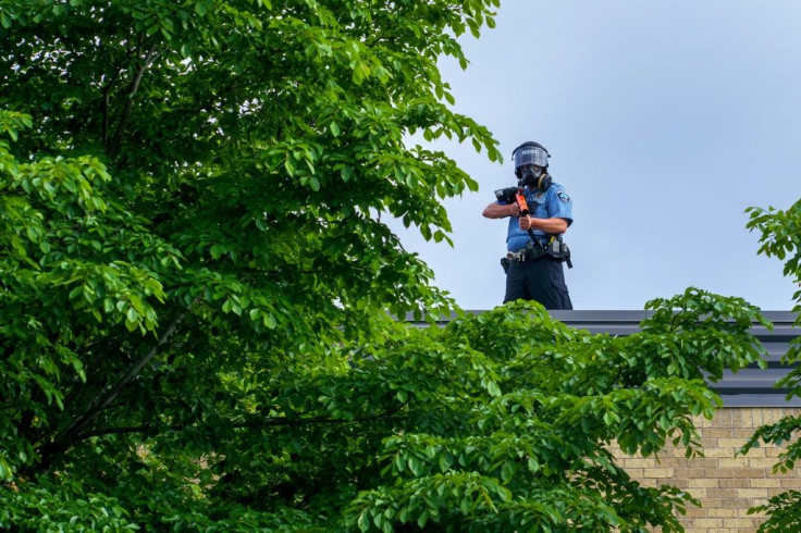 A police officer holds a projectile launcher during a demonstration in Minneapolis on May 27, 2020 calling for justice for George Floyd following his death