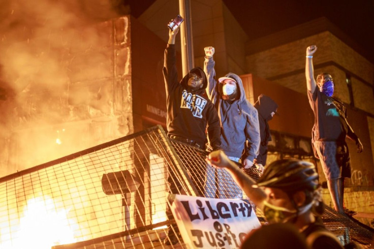 Protesters hold up their fists as flames rise behind them in Minneapolis, Minnesota, during demonstrations over the death of African American George Floyd in police custody