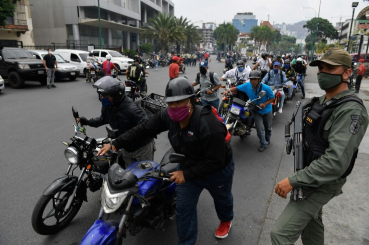 A soldier stands watch in Caracas, Venezuelas as bikers queue up to refuel amid a nationwide shortage