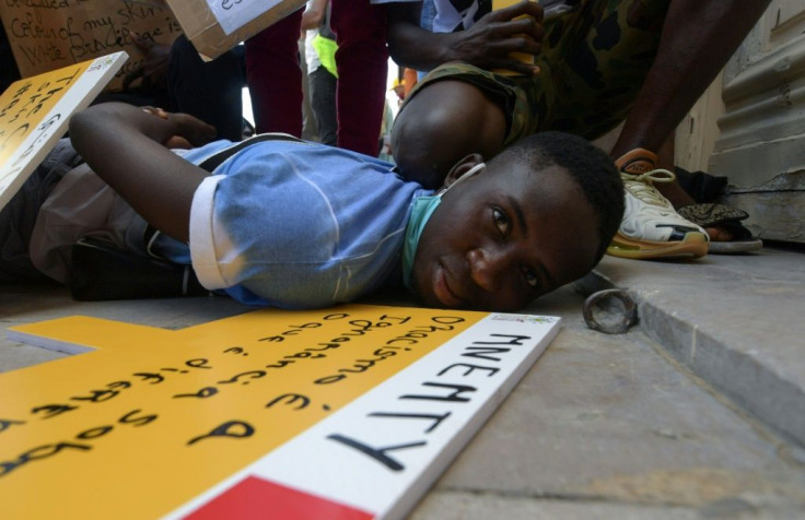 Youths participating in an anti-racism solidarity rally in the Tunisian capital Tunis, on June 6, 2020, re-enact the death of George Floyd