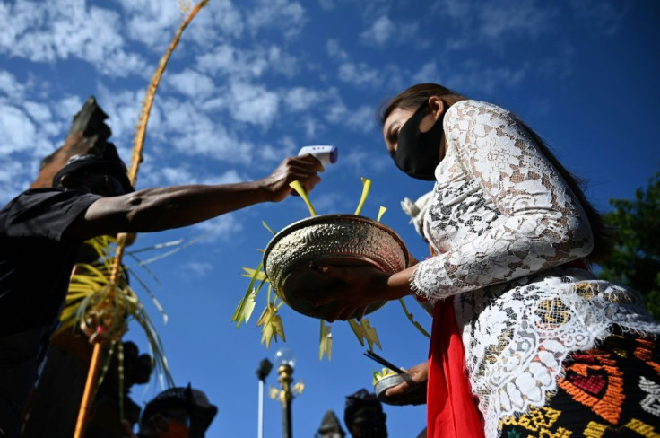 A Balinese woman masked against coronavirus has her temperature taken before a Hindu ceremony at Jagatnatha temple in Denpasar. The Indonesian island hopes to re-open to tourists in September