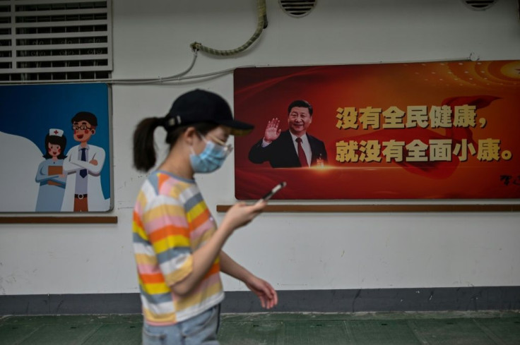 A woman in the original coronavirus epicenter of Wuhan walks in May 2020 past a picture of Chinese President Xi Jinping, who faced rare open domestic criticism over his virus response from a professor who has since been detained
