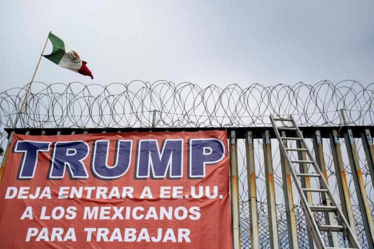 A Mexican flag and a banner reading 'Trump, let Mexicans enter the US to work' are seen during a demonstration by members of Border Angels and Alianza Migrante in the Mexican border city of Tijuana in February 2020
