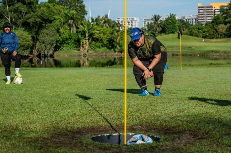 Get in the hole: Jamiatul Akmal Abdul Jabar watches as she sinks a "foot putt" in Shah Alam, on the outskirts of Kuala Lumpur, during a round of "footgolf"
