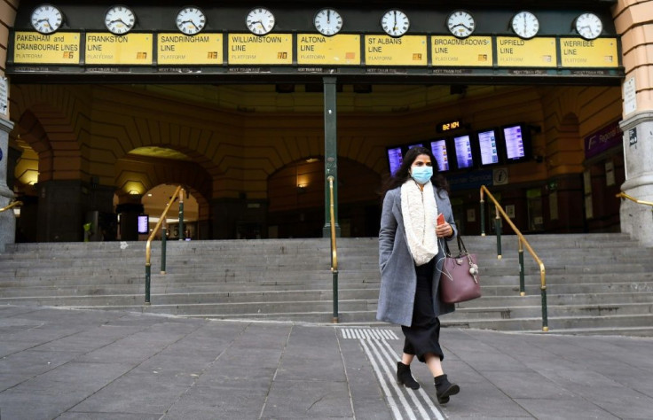 A commuter walks out of Melbourne's Flinders Street Station, wearing a mask