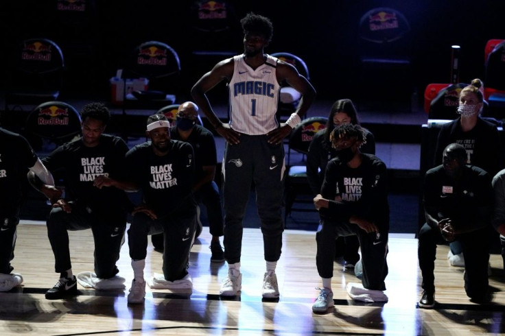 NBA player Jonathan Isaac stands as team-mates kneel during the national anthem ahead of Orlando's game with Brooklyn on Friday