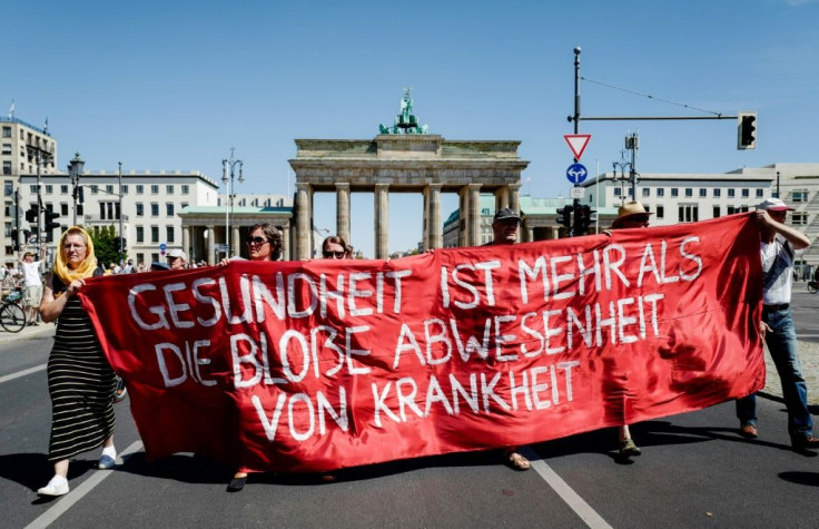 Marchers unveil a banner reading "health is more than the simple absence of illness"