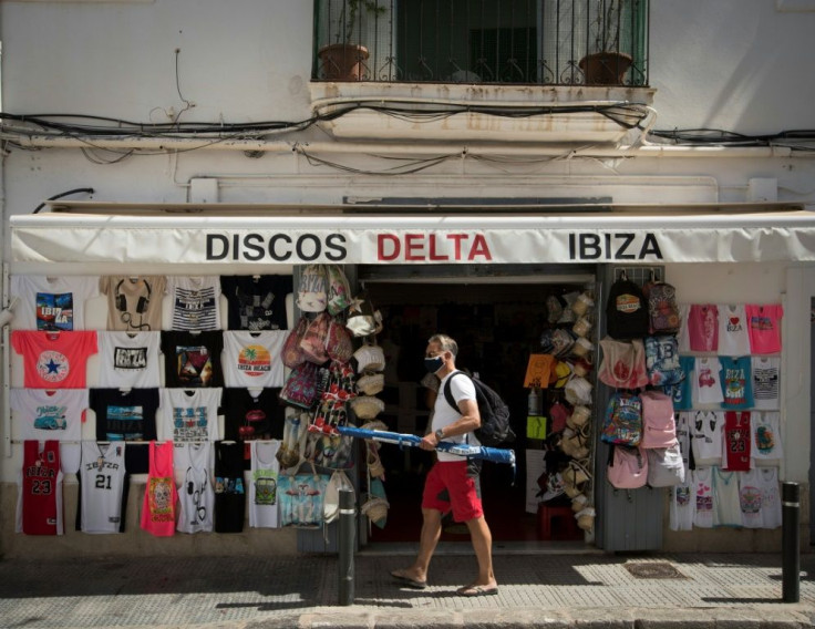 A man wearing a face mask walks in front of a store in Ibiza on July 31, 2020