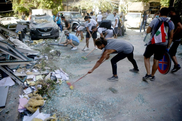 In small groups, volunteers energetically swept up glass beneath blown-out buildings, dragging them into plastic bags