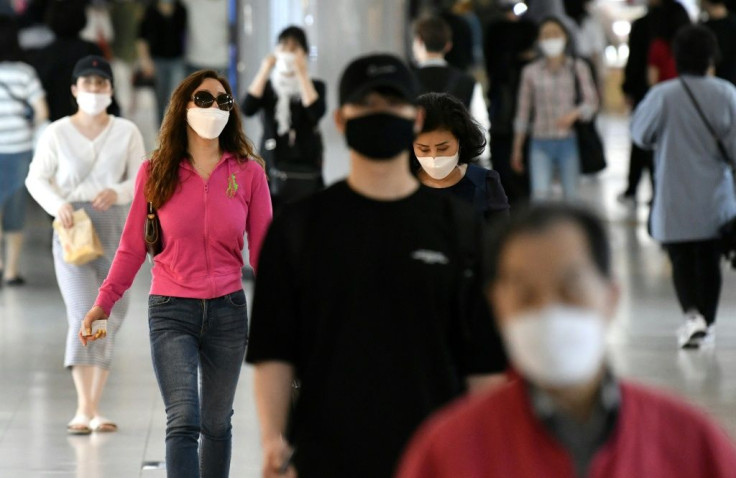 People wearing face masks walk through an underground shopping area in Seoul, South Korea in May