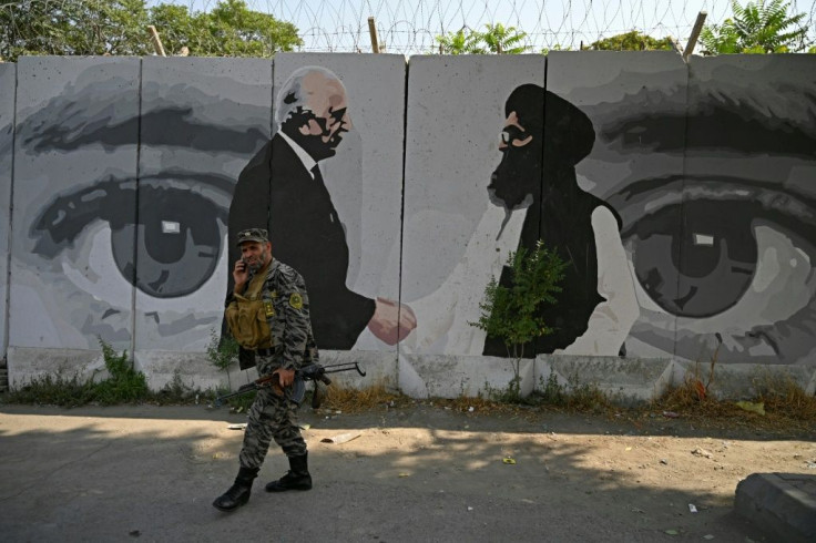 A soldier walks past a mural with images of US Special Representative for Afghanistan Reconciliation Zalmay Khalilzad (left) and Taliban co-founder Mullah Abdul Ghani Baradar