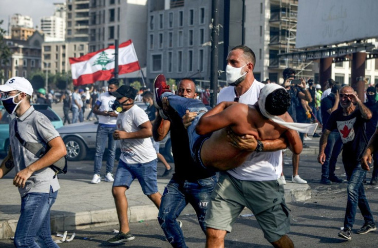 Lebanese basketball star Fadi al-Khatib carries a wounded demonstrator away from clashes in Beirut on Saturday, following a demonstration against a political leadership they blame for the monster explosion that killed more than 150 people