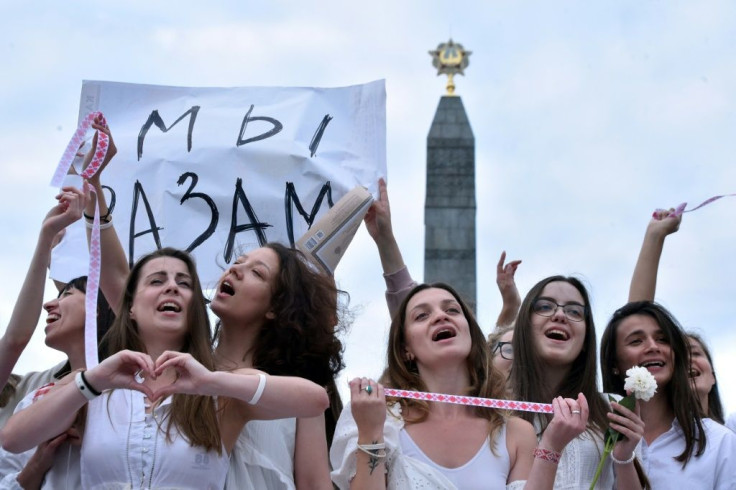 Women wearing white and holding flowers protest against police violence, in Minsk on Wednesday. The placard reads 'We are together'